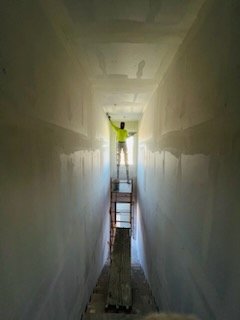 Workers lifting and placing drywall sheets on metal studs